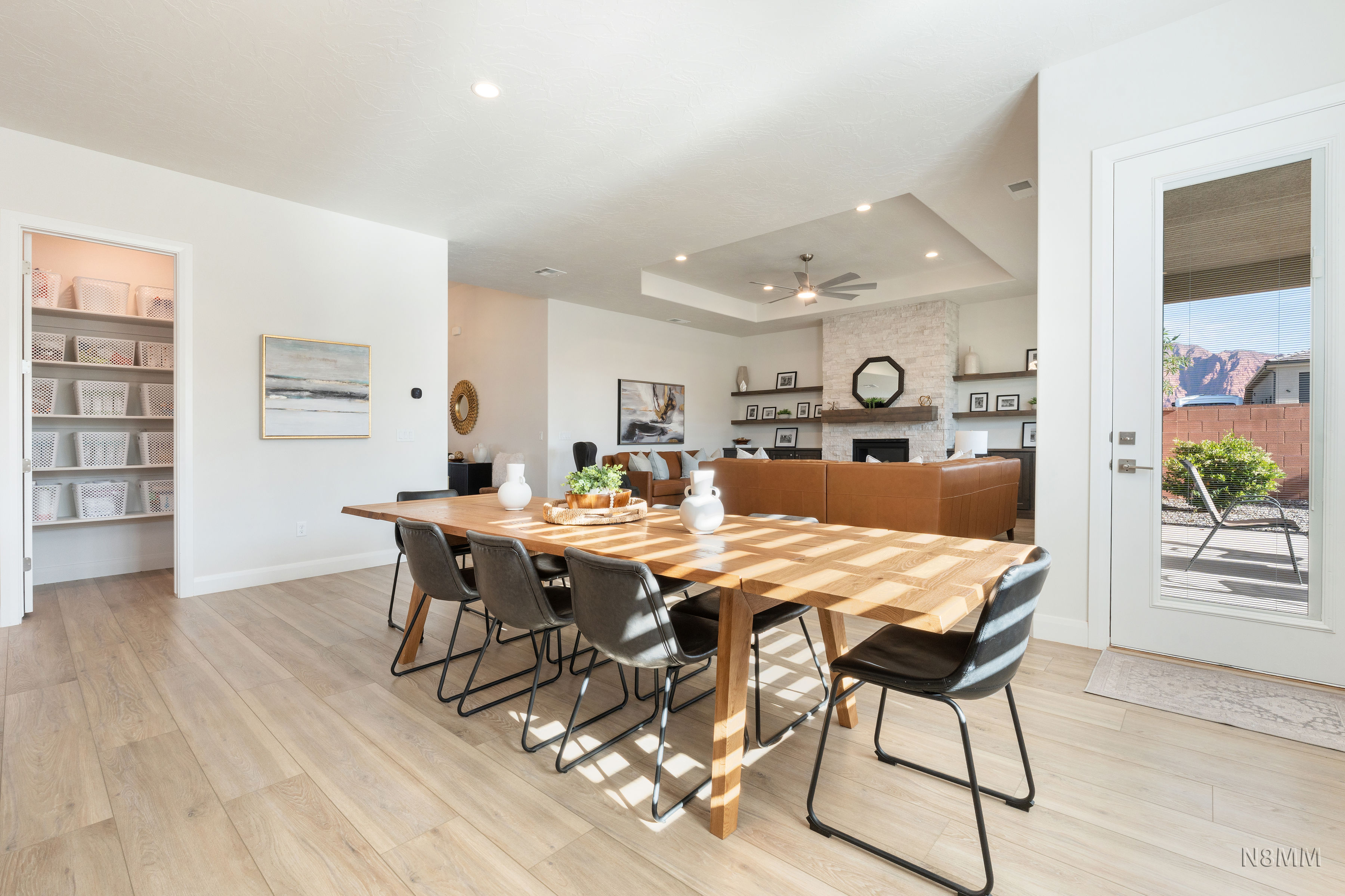 Dining space featuring light wood-style flooring, a fireplace, a tray ceiling, ceiling fan, and recessed lighting