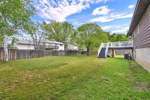 Partially fenced backyard featuring a deck and stairs
