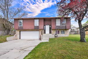 Raised ranch featuring a garage and concrete driveway