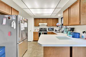 Kitchen featuring stainless steel appliances, light countertops, wood finish cabinetry, a peninsula, and recessed lighting
