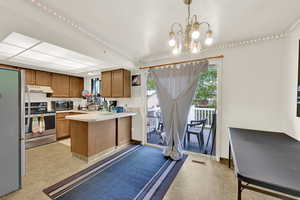 Kitchen featuring wood finish cabinets, stainless steel appliances, light countertops, a peninsula, and a chandelier