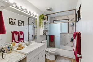 Bathroom with vanity and bath / shower combo with glass door