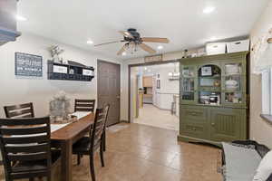 Dining area with a ceiling fan, light tile patterned flooring, and suspended lighting