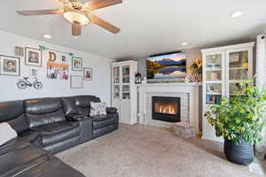 Carpeted living room featuring ceiling fan, recessed lighting, and a brick fireplace