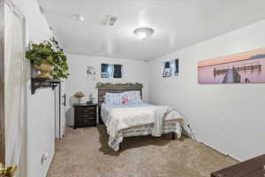 Bedroom featuring light carpet and a textured ceiling