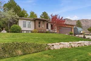View of front of property featuring a front yard, a garage, and brick siding