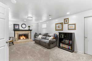 Living room with a textured ceiling, carpet floors, a tiled fireplace, and recessed lighting