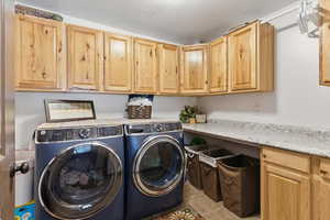 Laundry area with a textured ceiling, washer and clothes dryer, light tile patterned floors, and cabinet space