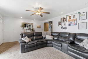 Carpeted living area with recessed lighting and ceiling fan