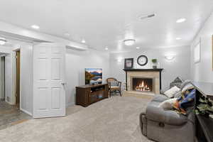 Living area with light carpet, a fireplace, a textured ceiling, and recessed lighting