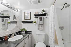 Full bathroom featuring vanity, shower / bathtub combination with curtain, and decorative backsplash