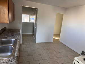 Kitchen featuring light tile patterned floors, dark countertops, and wood finish cabinets