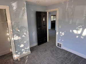 Unfurnished bedroom with dark carpet and a textured ceiling