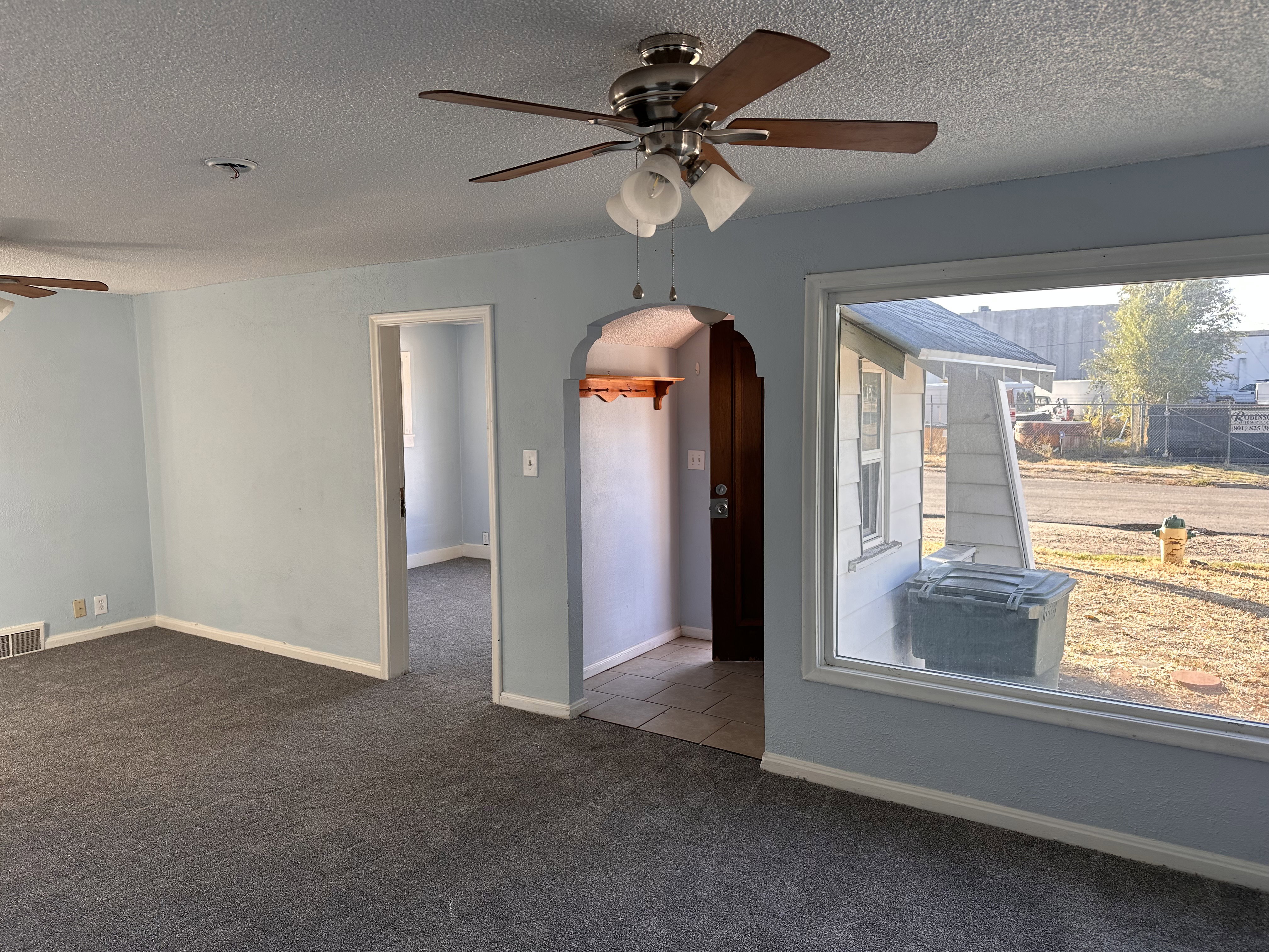 Spare room featuring ceiling fan, a textured ceiling, arched walkways, and dark colored carpet