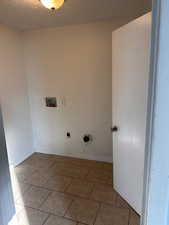 Laundry area featuring washer hookup, a textured ceiling, and light tile patterned floors