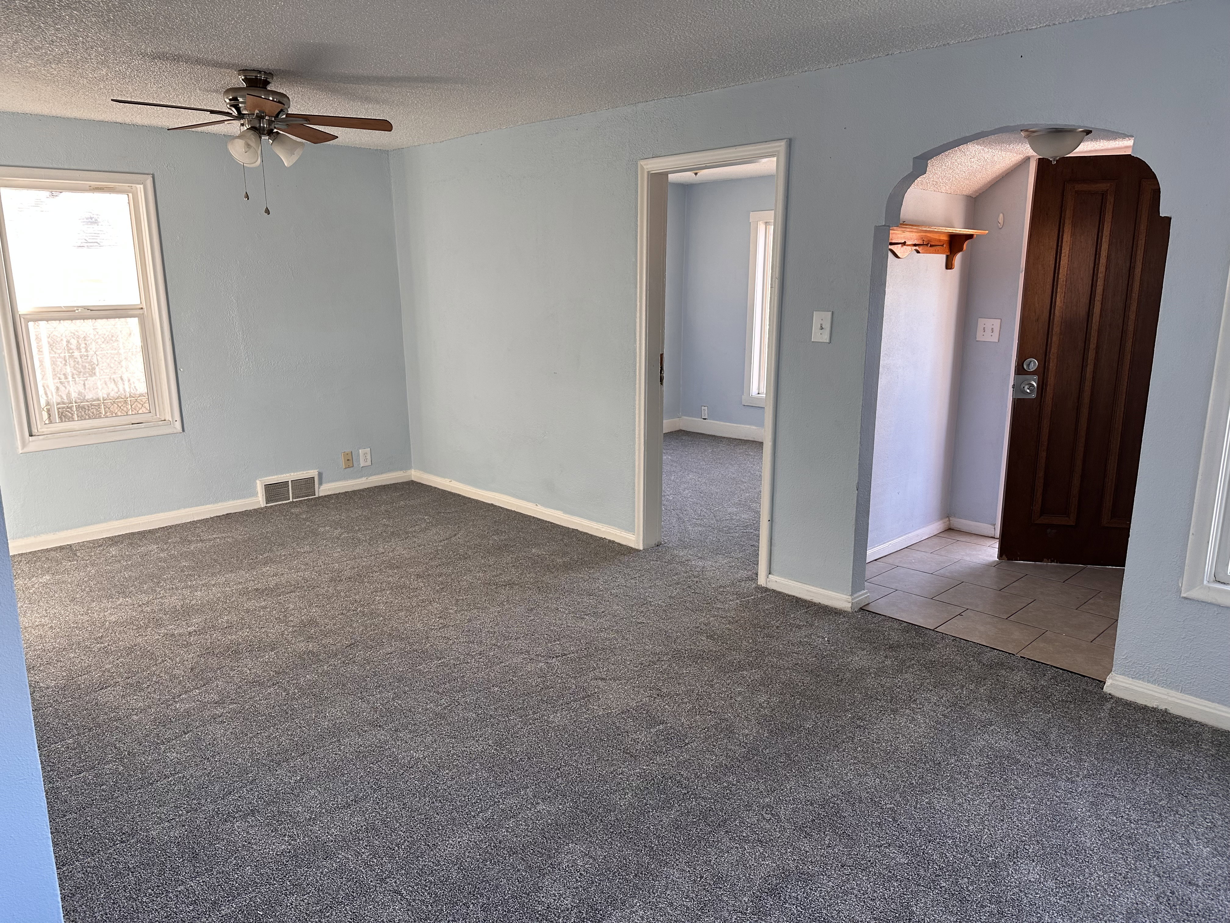 Spare room with arched walkways, carpet, ceiling fan, and a textured ceiling