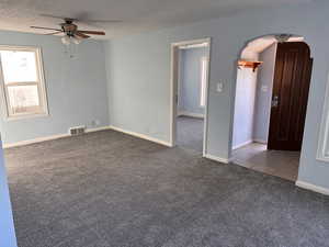 Spare room with arched walkways, carpet, ceiling fan, and a textured ceiling