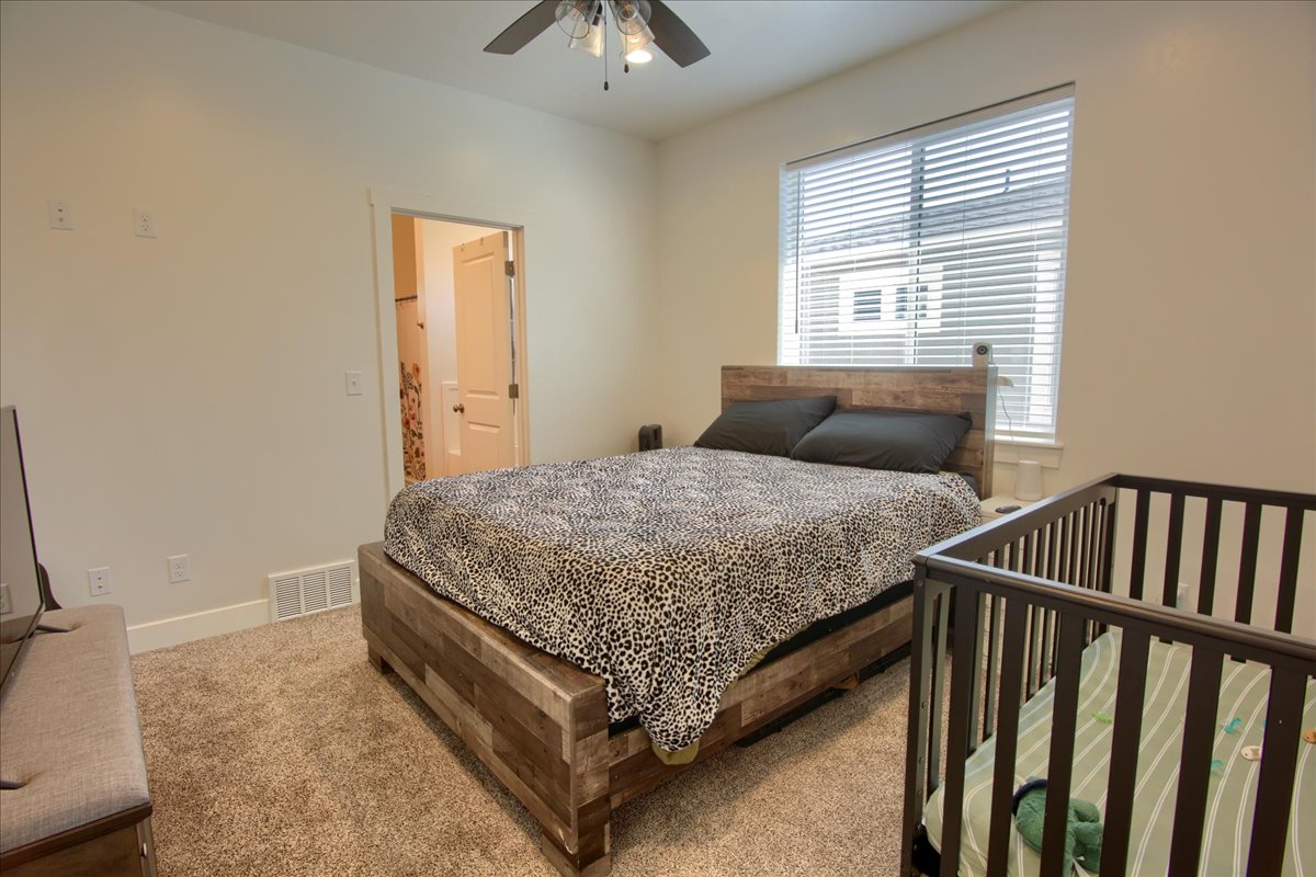 Carpeted bedroom featuring ensuite bath and a ceiling fan
