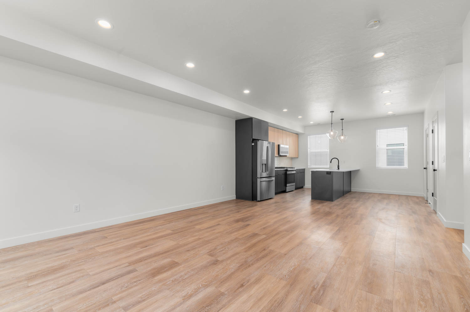 Kitchen with open floor plan, light wood finished floors, stainless steel appliances, and light countertops
