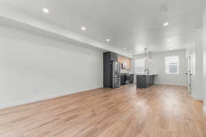 Kitchen with open floor plan, light wood finished floors, stainless steel appliances, and light countertops