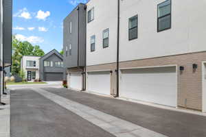 View of side of home featuring brick siding, stucco siding, and a garage