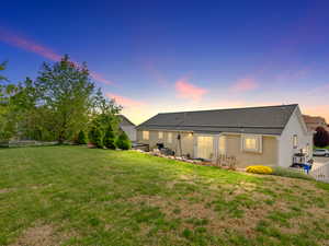 Rear view of property featuring a patio and a large flat grassy area