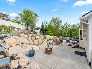 View of patio with an outdoor fire pit and a grill