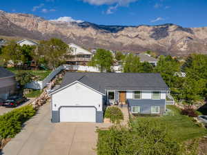 Ranch-style home with an attached garage, concrete driveway, a mountain view, R.V. parking and a front yard