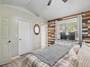 Primary Bedroom with vaulted ceiling, wooden accent walls, with walk-in closet and full bathroom