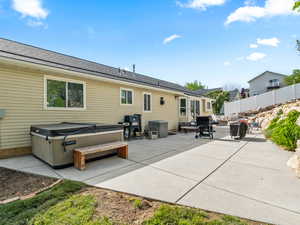 Rear view of property with a patio area, a hot tub included in sale of home
