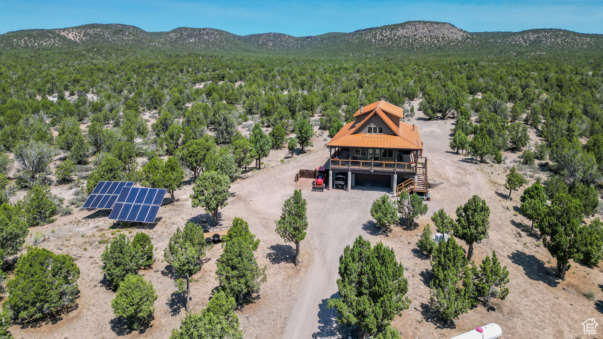 Aerial view of property and surrounding area featuring mountains and a heavily wooded area