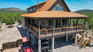 Back of house with an attached garage, a metal roof, a deck with mountain view, and gravel driveway