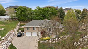 View of front facade with an attached garage, driveway, a chimney, roof with shingles, and stucco siding