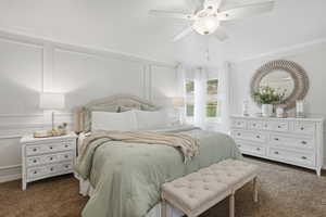 Bedroom with a decorative wall, dark carpet, and ceiling fan