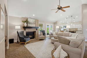 Carpeted living room featuring a ceiling fan, a brick fireplace, vaulted ceiling, and recessed lighting