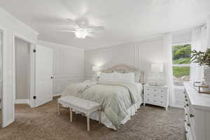 Bedroom featuring a decorative wall, dark carpet, ceiling fan, and a textured ceiling