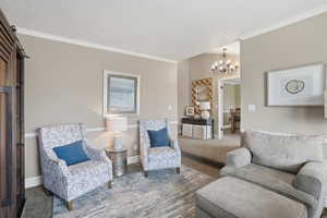 Sitting room featuring carpet floors, hanging lights, crown molding, and a textured ceiling