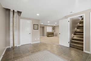Finished basement with stone tile flooring and recessed lighting with firepole