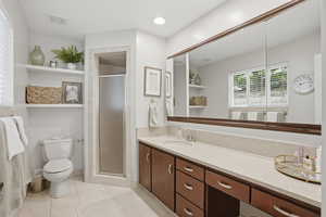 Bathroom with a shower stall, vanity, light tile patterned floors, and recessed lighting