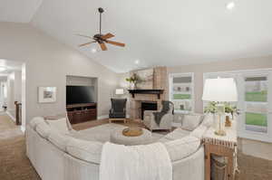 Living area featuring carpet, vaulted ceiling, a ceiling fan, a brick fireplace, and recessed lighting