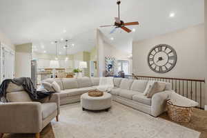 Living room featuring a ceiling fan, lofted ceiling, and suspended lighting