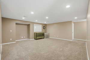 Below grade area with light carpet and recessed lighting
