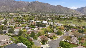 Aerial view of property and surrounding area featuring mountains and nearby suburban area