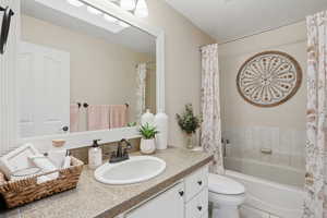 Full bath with vanity, shower / bath combo with shower curtain, and a textured ceiling
