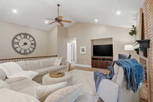Living area with ceiling fan, light colored carpet, vaulted ceiling, and recessed lighting