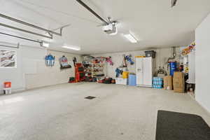 Garage with white refrigerator with ice dispenser and a garage door opener