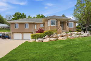 View of front facade with a shingled roof, brick siding, an attached garage, a front lawn, and concrete driveway