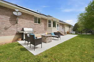 Back of property with brick siding, a fire pit, roof mounted solar panels, and a patio area
