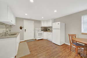 Kitchen featuring tasteful backsplash, white appliances, white cabinets, light wood-style flooring, and recessed lighting