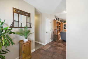 Hall featuring baseboards and dark stone finish flooring